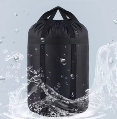 A black sleeping bag compression sack with a pull cord top, depicted with water splashing around it to illustrate its waterproof feature.