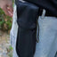 Black tool pouch attached to a person's waistband outdoors.