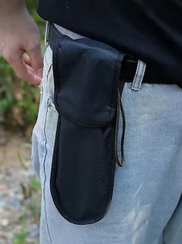 Black tool pouch attached to a person's waistband outdoors.