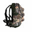 A camouflage backpack shown from the side against a plain white background, featuring a woodland tree-bark pattern in beige, brown, green, and black with dark green straps.