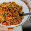 Person holding a bowl of quinoa salad with a spoon