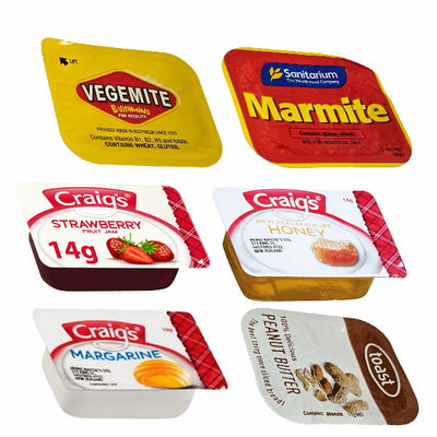 Collection of various food products including Vegemite, Marmite, Craig's strawberry fruit jam, honey, margarine, and Rospa peanut butter on a white background.