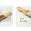 Two single serve packets, one labeled 'Cracked PEPPER' with a wooden spoonful of pepper next to it, and the other labeled 'Sea SALT' with a scoop of salt.